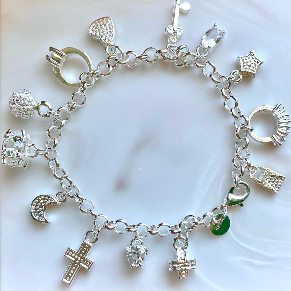 Silver charm bracelet with cross, moon, star, and other charms